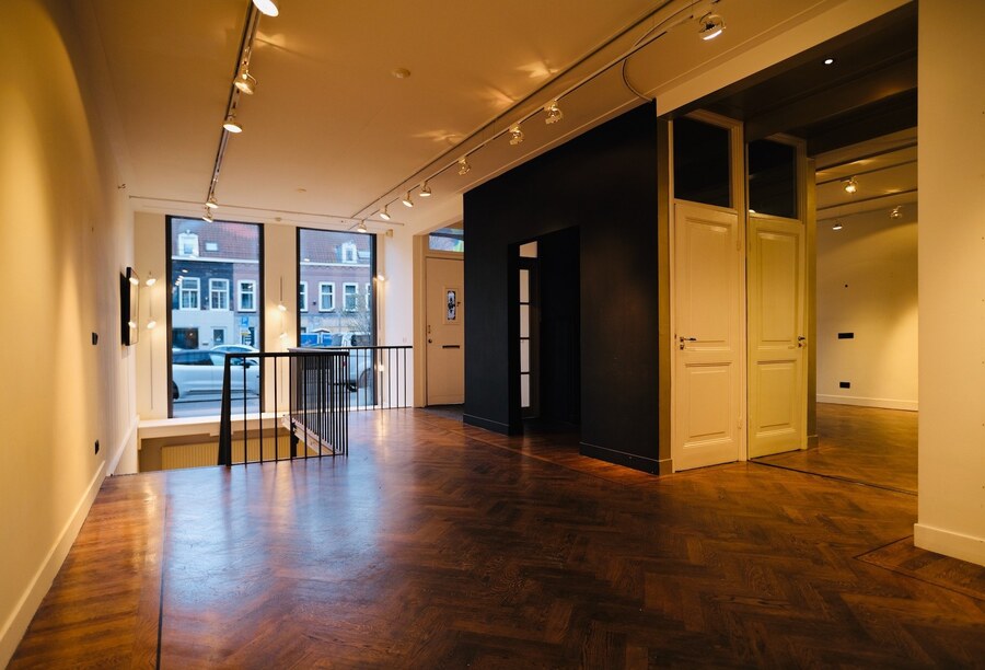 Warm interior gallery space at COSMOS152 with herringbone floors and track lighting