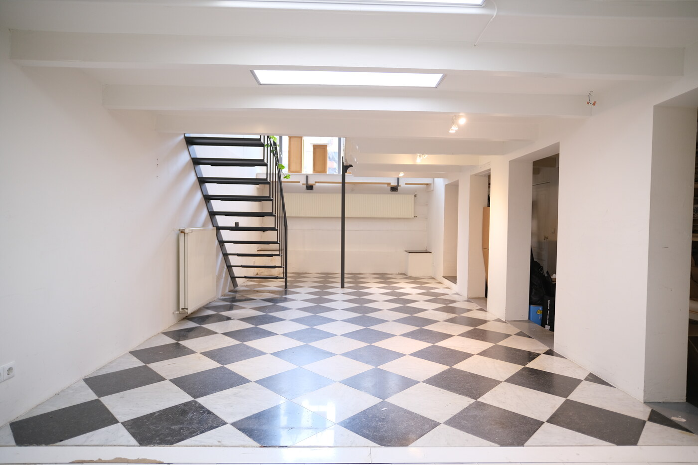 Lower-level space at COSMOS152 with checkerboard floor and stairs