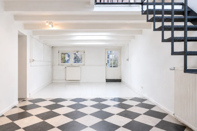 Finished impression of the empty basement with checkerboard floor and open stair