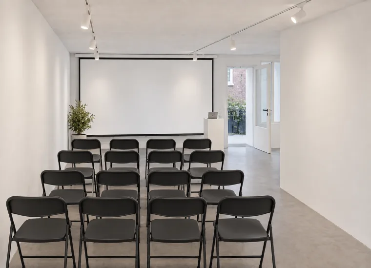Furnishing impression of a corporate presentation with black chairs and a lowered projection screen