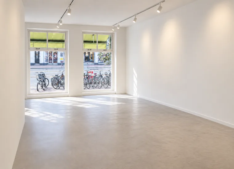 Finished impression of the empty grey-floored main space with street-facing windows